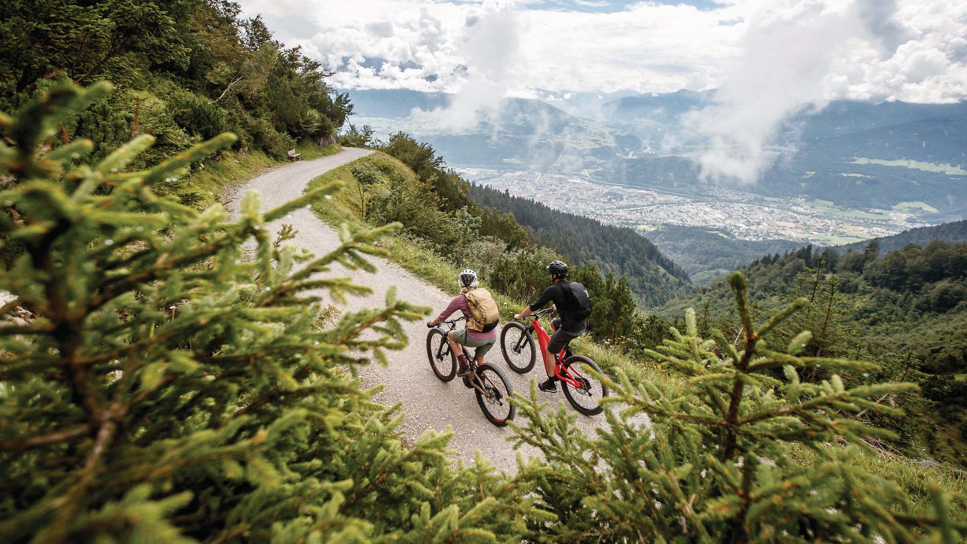 Dein Parkhotel in Matrei am Brenner Zwei Radfahrer auf einem Bergweg mit Blick auf Tal und Wolken