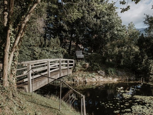 Dein Parkhotel in Matrei am Brenner Holzbrücke über einen Teich umgeben von Bäumen und Pflanzen