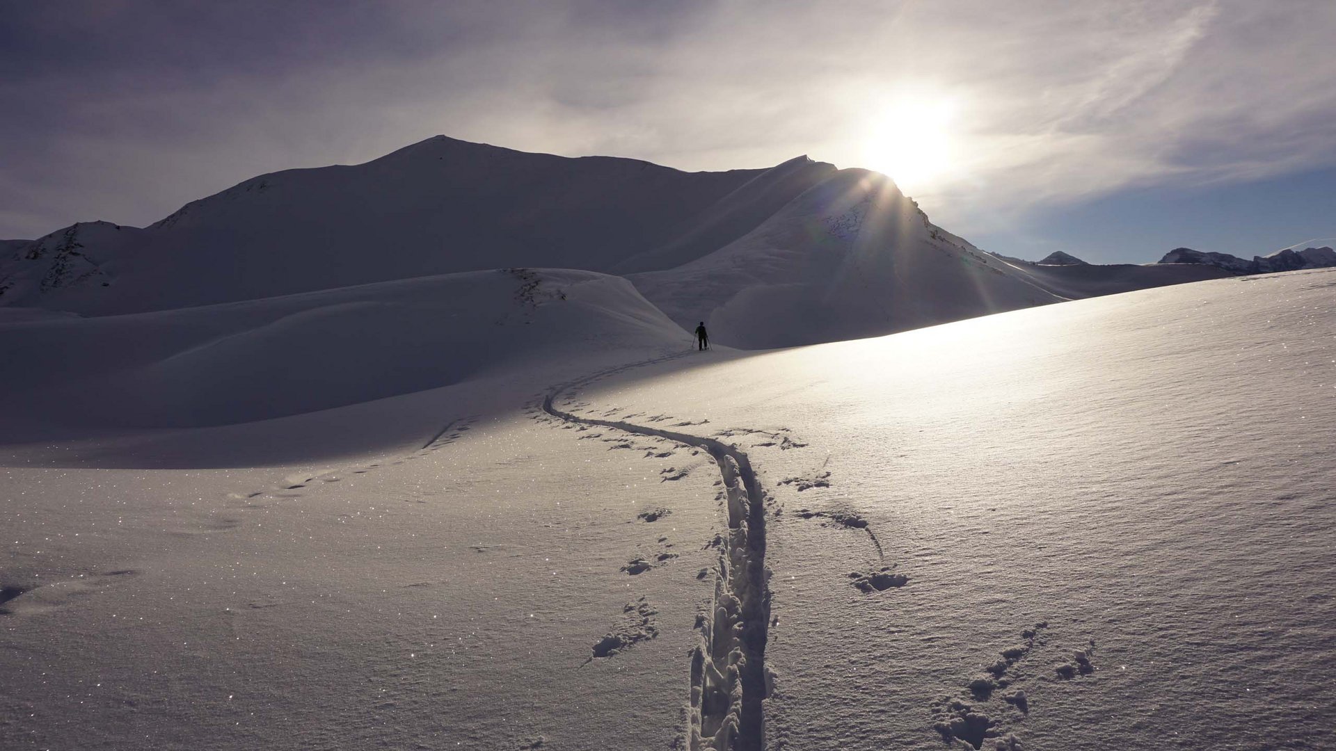 By car to Italy: stopover in Wipptal Ski tracks in snow with mountain and sun in the background