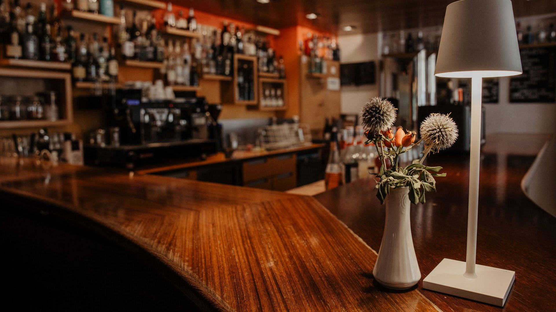 Herzlich willkommen in unserem Hotel in Matrei am Brenner Blumenstrauß und Lampe auf Holztresen in gemütlicher Bar