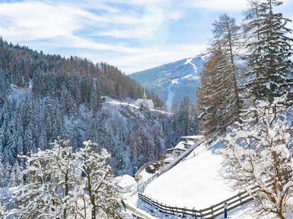 By car to Italy: stopover in Wipptal Snowy winter landscape with forest, mountains, and houses on a sunny day