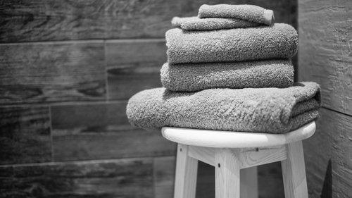 Herzlich willkommen in unserem Hotel in Matrei am Brenner Gefaltete Handtücher auf einem Hocker vor einer Holzfliesenwand