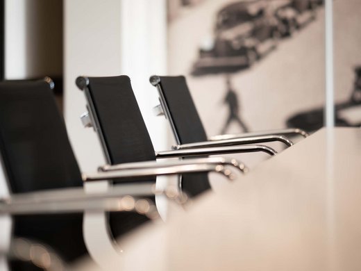 Seminarhotel in Tirol Schwarze Bürostühle an einem weißen Konferenztisch in einem modernen Raum